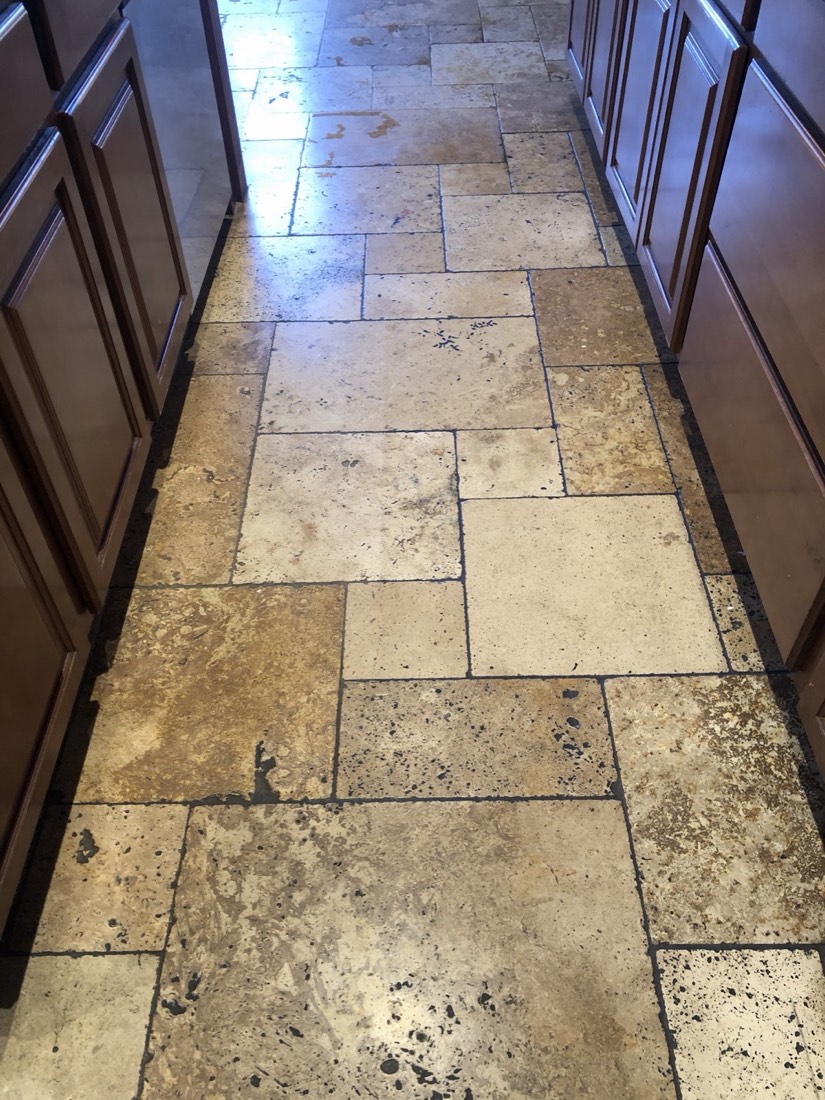 A clean travertine tile hallway beside dark cabinets